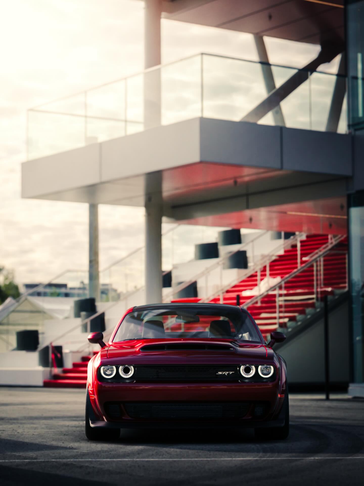 Gran Turismo 7 key art: a red Dodge Challenger SRT at a circuit grandstand